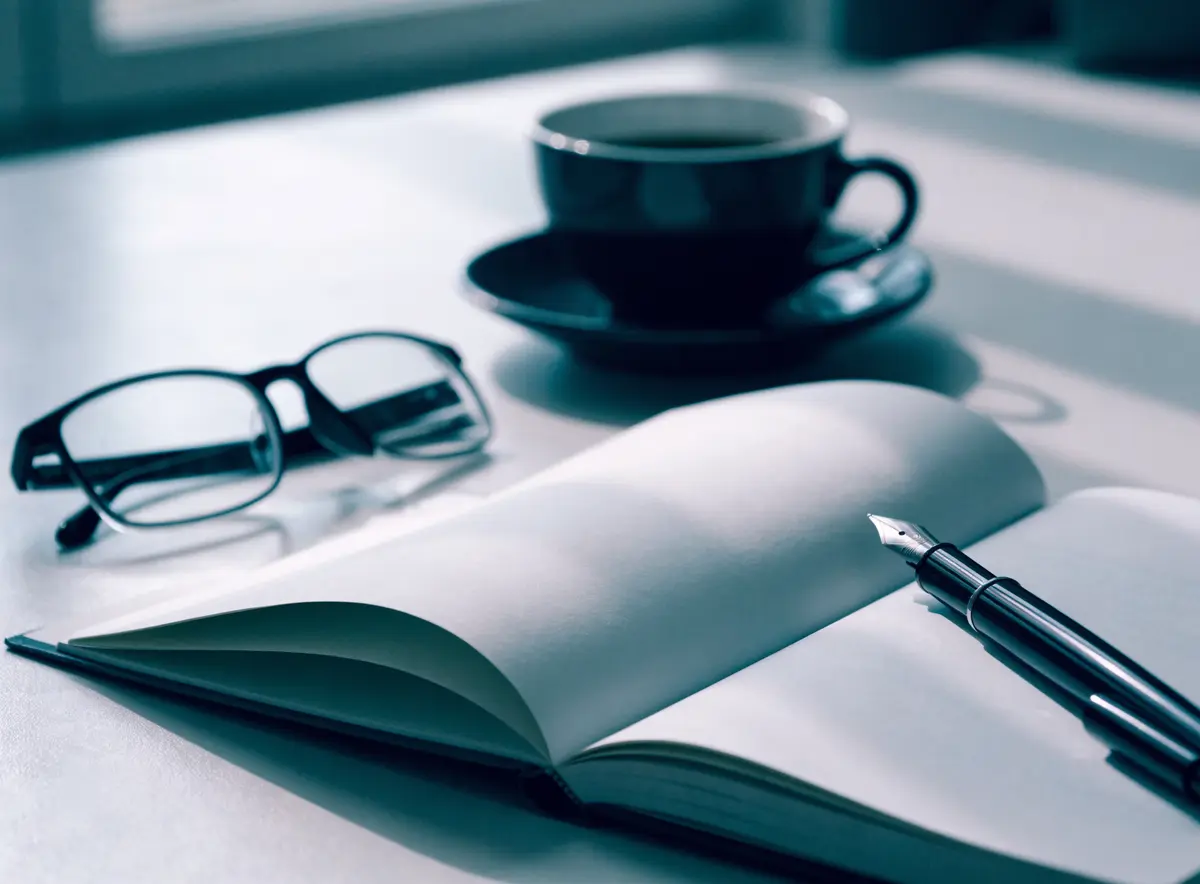 Bureau met een open notitieboek, pen en koffie